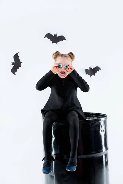 Liten flicka häxa i svart klänning över magiska tillbehör. Halloween, kvällens studio. — Stockfoto