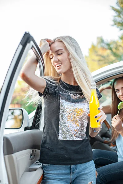 Le giovani donne in macchina sorridenti e che bevono succo — Foto Stock