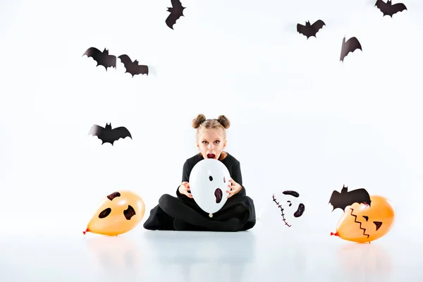 Liten flicka häxa i svart klänning över magiska tillbehör. Halloween, kvällens studio. — Stockfoto