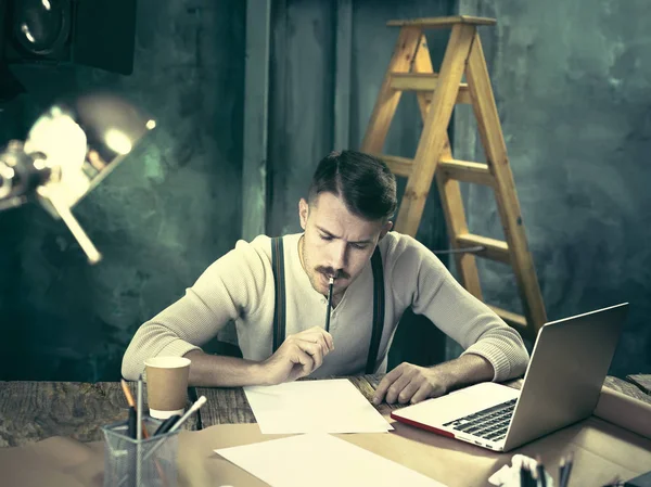 Retrato de un hombre de negocios barbudo que trabaja con su cuaderno en el estudio loft . — Foto de Stock