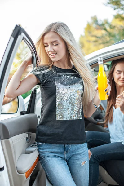 As jovens mulheres no carro sorrindo e bebendo suco — Fotografia de Stock