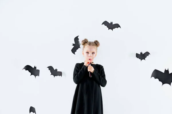 Niña bruja en vestido negro sobre accesorios mágicos. Halloween, la noche del estudio . — Foto de Stock