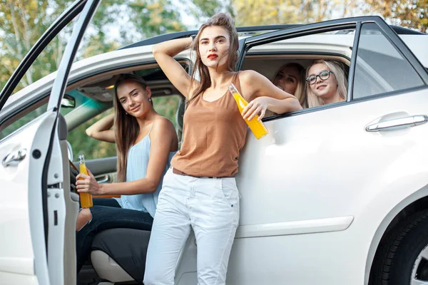 Молоді жінки в машині посміхаються і п'ють сік — стокове фото