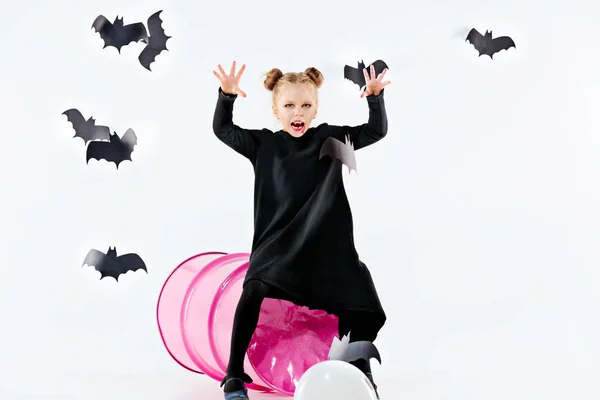 Liten flicka häxa i svart klänning över magiska tillbehör. Halloween, kvällens studio. — Stockfoto