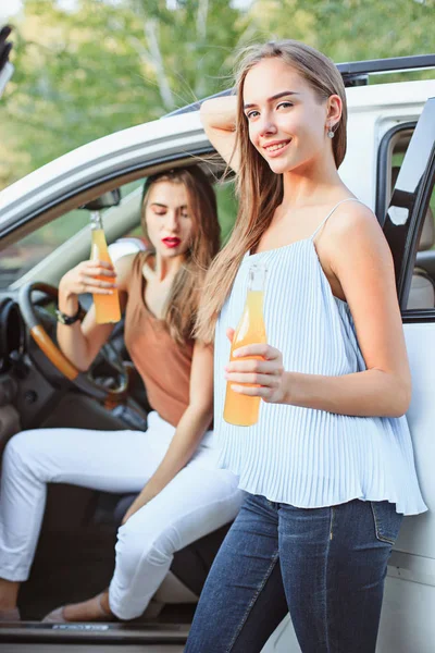 Le giovani donne in macchina sorridenti e che bevono succo — Foto Stock