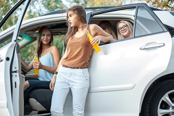 As jovens mulheres no carro sorrindo e bebendo suco — Fotografia de Stock