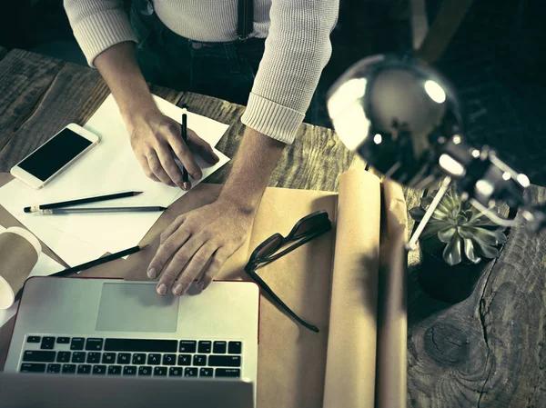 Винтажный хипстер с деревянным верхом на рабочем столе, мужские руки с ноутбуком и с карандашом в руках — стоковое фото