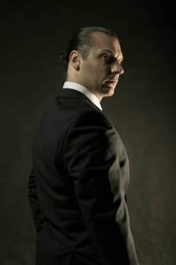 Koyu arka plan üzerinde siyah elbiseli çekici bir adam