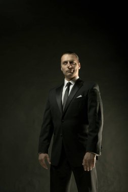 Koyu arka plan üzerinde siyah elbiseli çekici bir adam