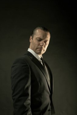 Koyu arka plan üzerinde siyah elbiseli çekici bir adam