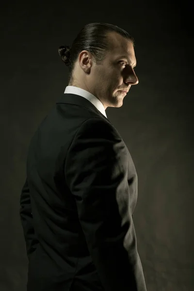 Koyu arka plan üzerinde siyah elbiseli çekici bir adam — Stok fotoğraf