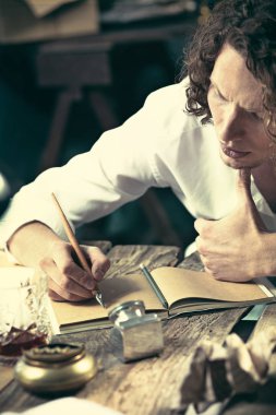 Yazar iş başında. Masada oturan ve bir şey onun eskiz defteri yazma yakışıklı genç yazar