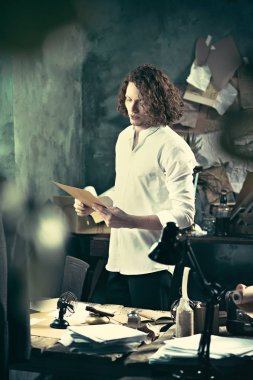 Yazar iş başında. Masanın ayakta ve zihninde bir şey yapma yakışıklı genç yazar