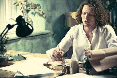 Yazar iş başında. Masada oturan ve bir şey onun eskiz defteri yazma yakışıklı genç yazar