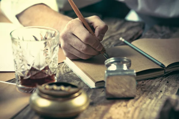 Escritor no trabalho. As mãos do jovem escritor sentado à mesa e escrevendo algo em seu sketchpad — Fotografia de Stock