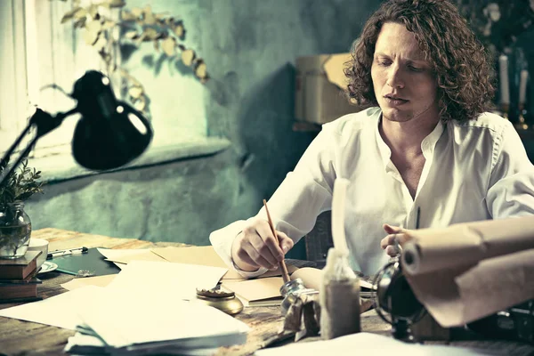 Yazar iş başında. Masada oturan ve bir şey onun eskiz defteri yazma yakışıklı genç yazar