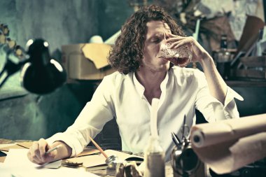 Yazar iş başında. Masada oturan ve bir şey onun eskiz defteri yazma yakışıklı genç yazar