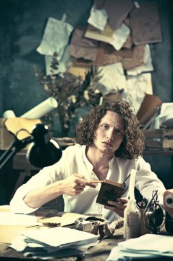 Yazar iş başında. Masada oturan ve bir şey onun eskiz defteri yazma yakışıklı genç yazar