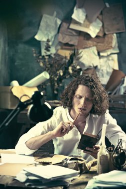 Yazar iş başında. Masada oturan ve bir şey onun eskiz defteri yazma yakışıklı genç yazar