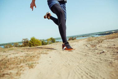 Koşu sporu. Erkek koşucu, doğa manzarasında koşuyor. Uygun kaslı erkek atlet maraton koşusu için antrenman parkuru.