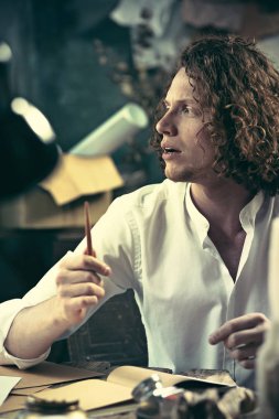 Yazar iş başında. Masada oturan ve bir şey onun eskiz defteri yazma yakışıklı genç yazar