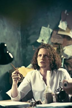 Yazar iş başında. Masada oturan ve bir şey onun eskiz defteri yazma yakışıklı genç yazar