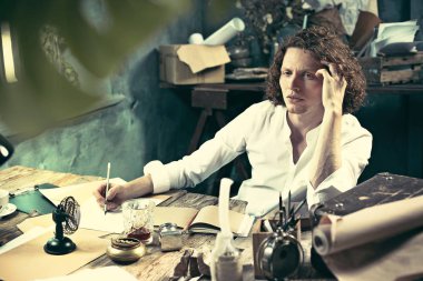 Yazar iş başında. Masada oturan ve bir şey onun eskiz defteri yazma yakışıklı genç yazar