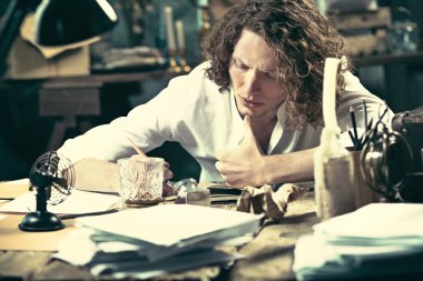 Yazar iş başında. Masada oturan ve bir şey onun eskiz defteri yazma yakışıklı genç yazar