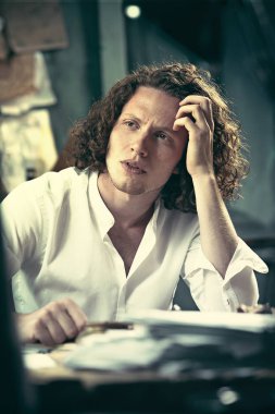 Yazar iş başında. Masada oturan ve bir şey onun eskiz defteri yazma yakışıklı genç yazar