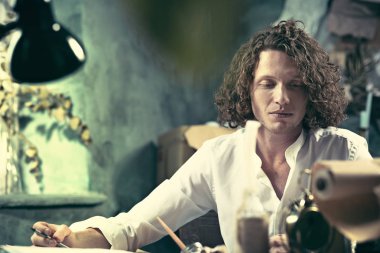 Yazar iş başında. Masada oturan ve bir şey onun eskiz defteri evde yazma yakışıklı genç yazar