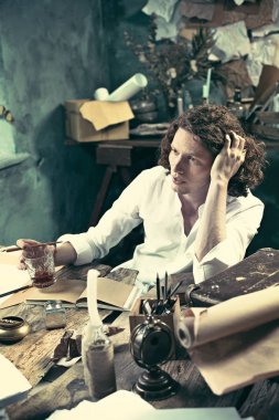 Yazar iş başında. Masada oturan ve bir şey onun eskiz defteri evde yazma yakışıklı genç yazar