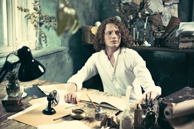 Yazar iş başında. Masada oturan ve bir şey onun eskiz defteri evde yazma yakışıklı genç yazar