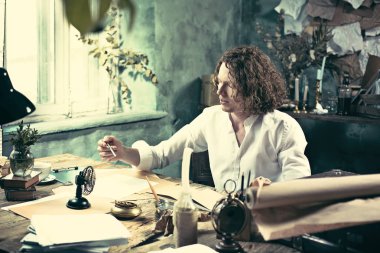 Yazar iş başında. Masada oturan ve bir şey onun eskiz defteri yazma yakışıklı genç yazar