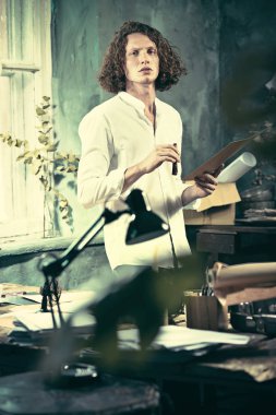 Yazar iş başında. Masanın ayakta ve zihninde bir şey yapma yakışıklı genç yazar