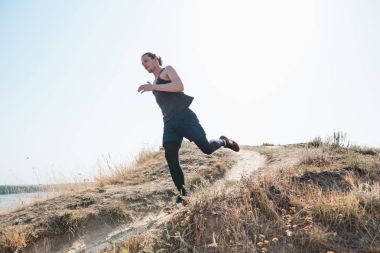 Koşu sporu. Erkek koşucu, doğa manzarasında koşuyor. Uygun kaslı erkek atlet maraton koşusu için antrenman parkuru.