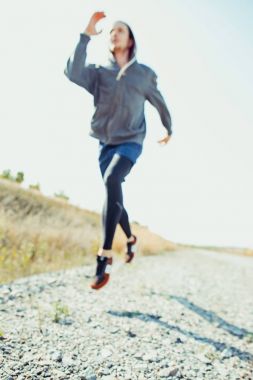 Koşu sporu. Erkek koşucu, doğa manzarasında koşuyor. Uygun kaslı erkek atlet maraton koşusu için antrenman parkuru.