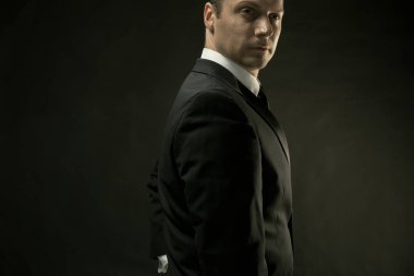 Koyu arka plan üzerinde siyah elbiseli çekici bir adam