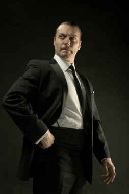 Koyu arka plan üzerinde siyah elbiseli çekici bir adam