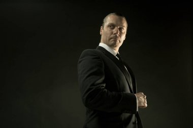 Koyu arka plan üzerinde siyah elbiseli çekici bir adam