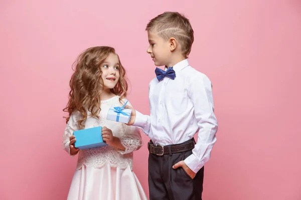 Chlapec a dívka stojící ve studiu na růžovém pozadí — Stock fotografie