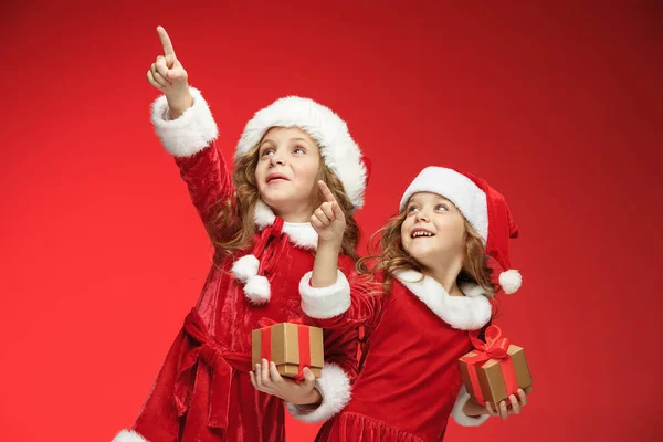 Duas meninas felizes em chapéus de Papai Noel com caixas de presente — Fotografia de Stock