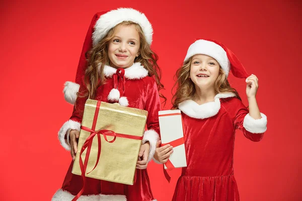 Duas meninas felizes em chapéus de Papai Noel com caixas de presente no estúdio — Fotografia de Stock