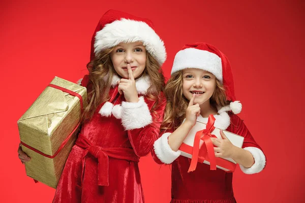 Duas meninas felizes em chapéus de Papai Noel com caixas de presente no estúdio — Fotografia de Stock
