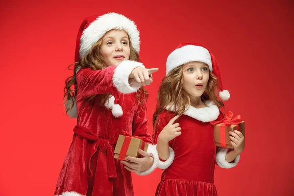 Duas meninas felizes em chapéus de Papai Noel com caixas de presente no estúdio — Fotografia de Stock