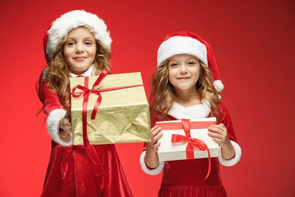 Две счастливые девушки в шляпах Санта-Клауса с подарочными коробками в студии — стоковое фото
