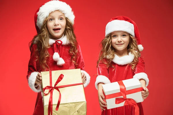Две счастливые девушки в шляпах Санта-Клауса с подарочными коробками в студии — стоковое фото