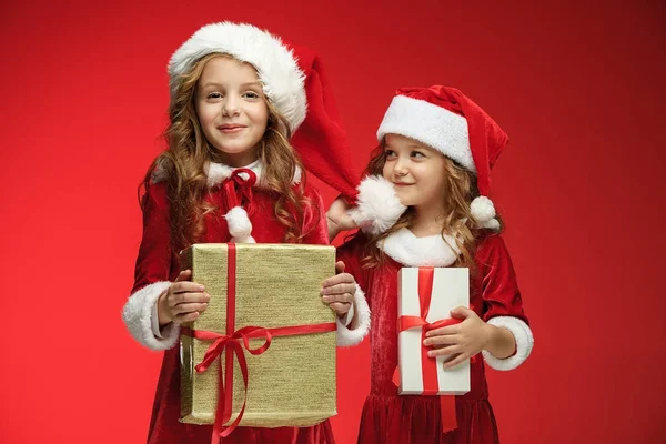 Duas meninas felizes em chapéus de Papai Noel com caixas de presente no estúdio — Fotografia de Stock