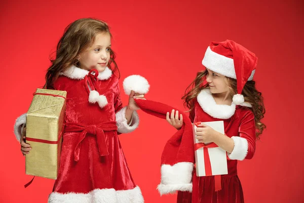 Duas meninas felizes em chapéus de Papai Noel com caixas de presente no estúdio — Fotografia de Stock