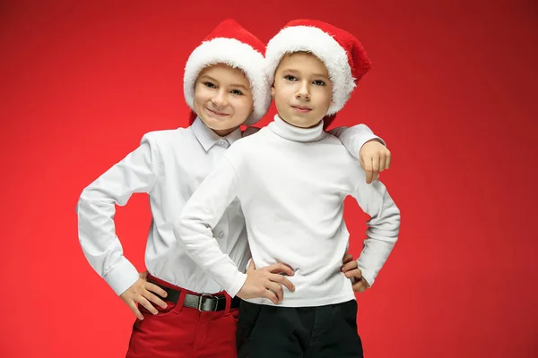 Два счастливых мальчика в шляпах Санта-Клауса с подарочными коробками в студии — стоковое фото
