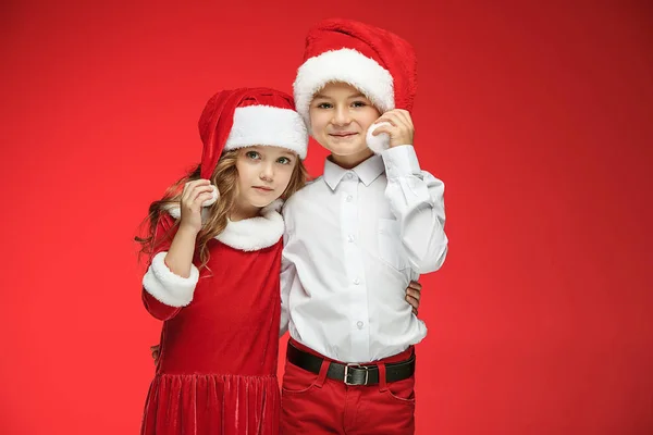 Två glada pojke och flicka i santa claus hattar med presentaskar på studio — Stockfoto